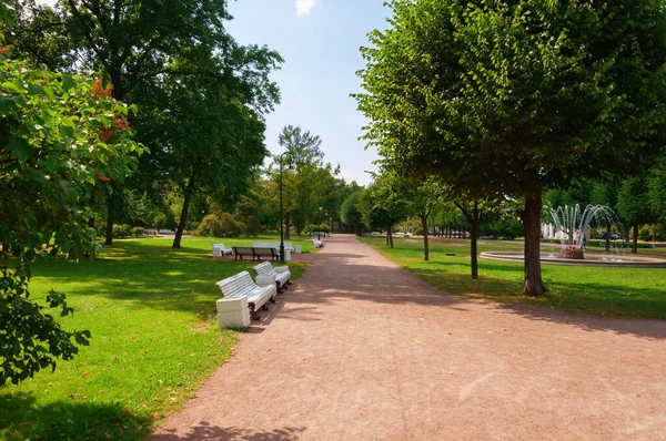 Beyaz bankları ve çeşmesi olmayan ıssız bir park. Yaz. Gün