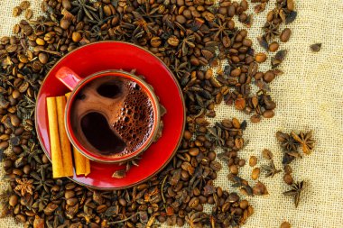 Kahverengi bir arka planda kahve ve kahve çekirdekli kırmızı fincan ve çay tabağı..