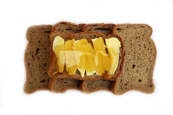 Grijze stukken brood met boter en honing op een witte achtergrond. — Stockfoto