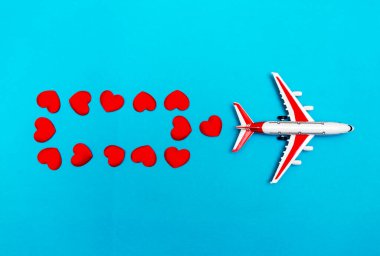 Mavi arka planda uçak oyuncağı ve kalp, aşk yolculuğu konsepti.