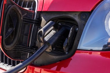 Park halindeki elektrikli arabanın, şarj istasyonuna bağlı aracın görüntüsünü kapat