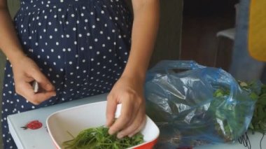 Mutfakta bir kadın taze sebze salatası hazırlıyor.