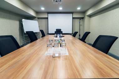 Conference room for business meetings a large table in the middle of the room around comfortable chairs, there is water on the table