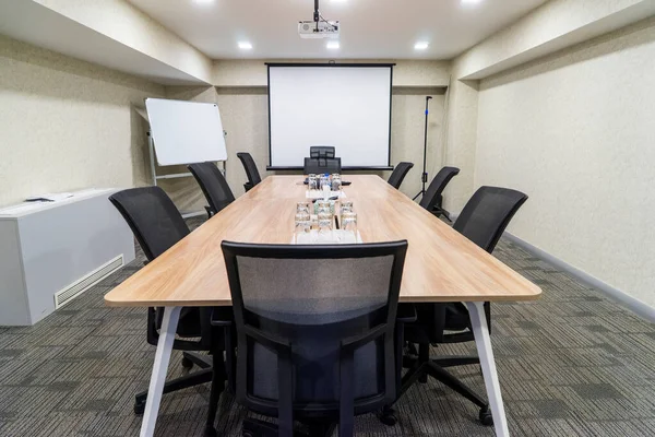 Conference room for business meetings a large table in the middle of the room around comfortable chairs, there is water on the table