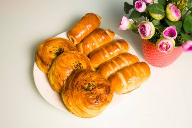 Masanın üzerinde beyaz bir tabağa doldurulmuş taze pişmiş rulo.