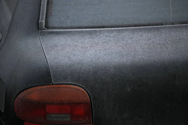 Rear glass, trunk lid and brake light from a mazda 121 DB car, black-green, sprinkled with the first frost. 