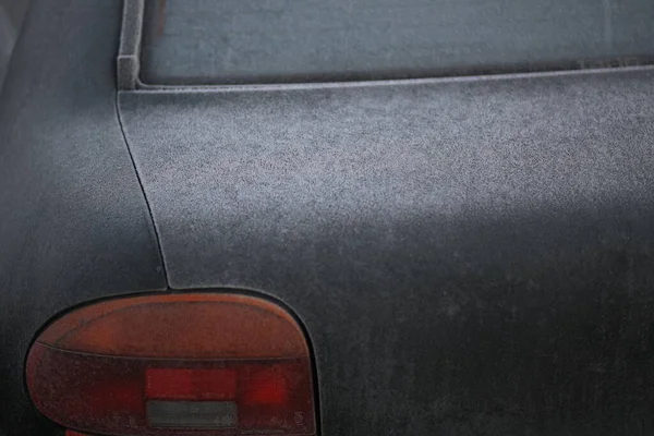 On a crisp, frosty morning, the soft vinyl sliding roof of a car clearly out of the weather as a convertible covered in rain. 