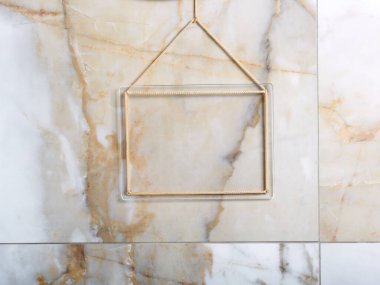 Görüntü eklemek için şeffaf plastik mozaik akrilik plaka ya da metin peyzaj oryantasyonu asılı çerçevenin deliklerinden şık, soyut, klasik, parlak mermer bir duvarın arka planına doğru uzanan altın bir kordon üzerinde asılı.