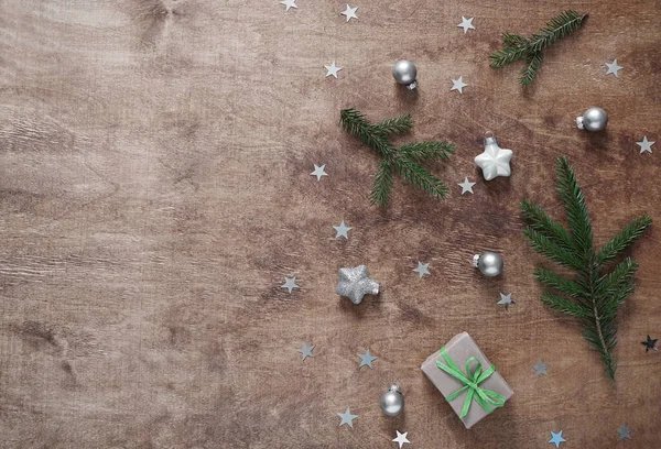 Noel kompozisyonu. Noel hediyesi, çam dalları ve tahtada gümüş yıldızlar. Üst görünüm, düz görünüm, kopyalama alanı