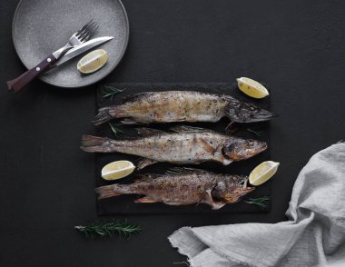 Kızarmış turna balığı, turna balığı ve levrek. Koyu bir arka planda bir plaka ve peçeteyle taş bir tahtaya konmuş. Üst manzara. Boşluğu kopyala