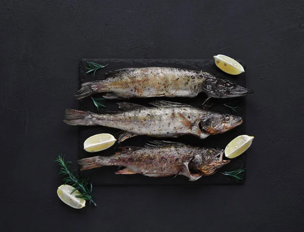 Kızarmış turna balığı, turna balığı ve levrek. Koyu bir arka planda, taş bir tahtada. Üst manzara. Boşluğu kopyala