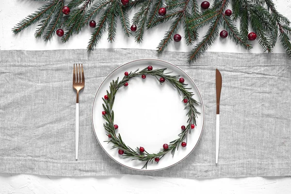 Yaban mersinli ve biberiyeli Noel tabağı açık gri peçeteyle süslenmiş ağaç dalları, üst manzara, kopyalama alanı