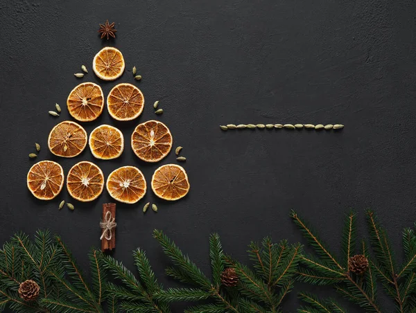 Kurutulmuş portakal dilimleri anason yıldızları, tarçın çubukları, köknar ağacı dalları ve üst manzaralı bir tahtanın üzerinde noel ağacı şeklinde lai. Boşluğu kopyala