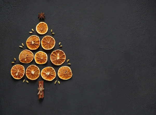 Kurutulmuş portakal dilimleri, üzerinde tarçın çubukları olan bir tahtanın üzerinde noel ağacı şeklinde duruyordu. Boşluğu kopyala