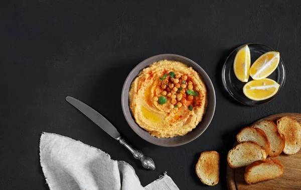 bowl of hummus with paprika on grey kitchen table, top view. copy space