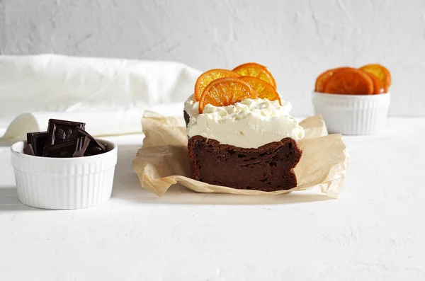 Beyaz peynirli ve şekerli portakallı ev yapımı çikolatalı kek ve beyaz arka planda pişirme kağıdı. Seçici odak, boşluğu kopyala
