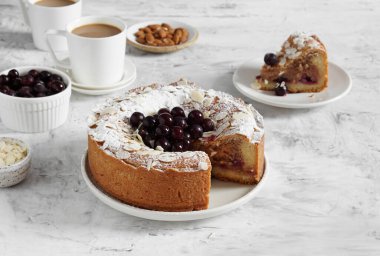 Bir fincan kahve ve bir dilim turtayla servis edilen dondurulmuş çilekli frangipan turtası.