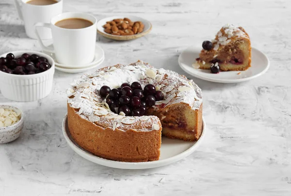 Bir fincan kahve ve bir dilim turtayla servis edilen dondurulmuş çilekli frangipan turtası.