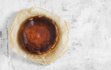 Beyaz zemin üzerinde fırınlanmış kağıt üzerinde ev yapımı Bask peynirli kekinin üst görünümü, boşluğu kopyala