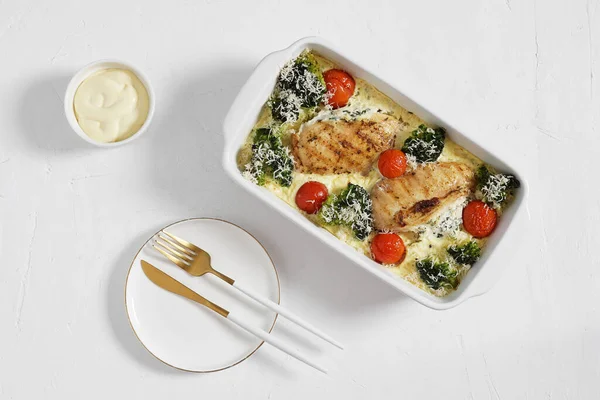 Brokoli ve domatesli fırında tavuk filetosu, beyaz arka planda tabak ve çatal bıçakla servis ediliyor, keto diyeti, üst görünüm.