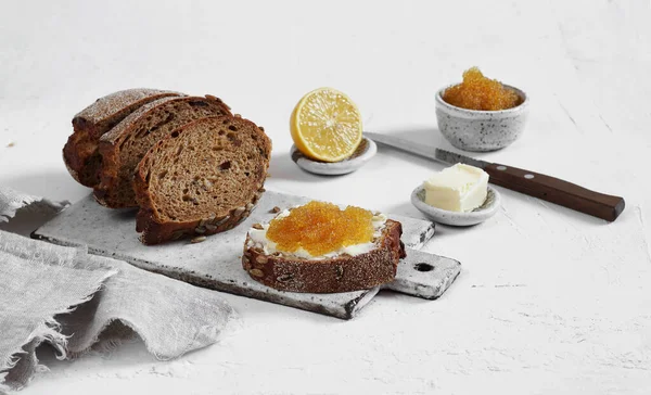 Ekmeğin üzerinde turna balığı havyarı ve beyaz arka planda tereyağı.