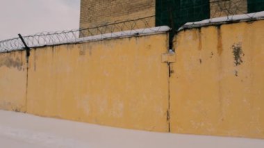 Old Soviet prison in winter, high fence with barbed wire and snow