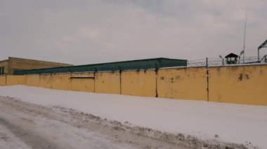 Old Soviet prison in winter, high fence with barbed wire and snow