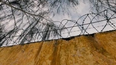 Old Soviet prison in winter, high fence with barbed wire and snow