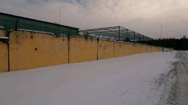 Old Soviet prison in winter, high fence with barbed wire and snow