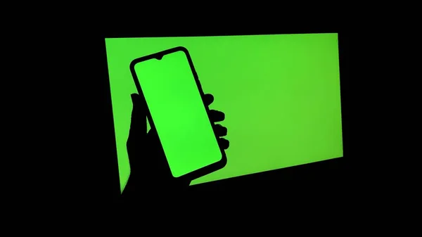電子デバイス上のクロマキー 携帯電話やモニター 緑の画面と手が光が存在しない状態で画面をスクロール — ストック写真