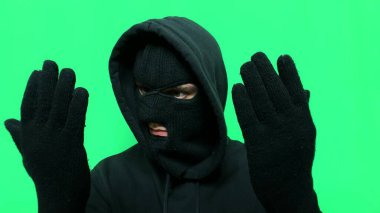 Kızgın genç adam bir hırsız oldu ve ilk mağaza soygunu için malzemelerini ve giysilerini yeşil bir arka planda hazırladı.