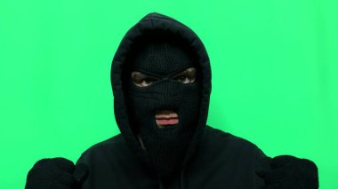 Kızgın genç adam bir hırsız oldu ve ilk mağaza soygunu için malzemelerini ve giysilerini yeşil bir arka planda hazırladı.