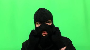 Kızgın genç adam bir hırsız oldu ve ilk mağaza soygunu için malzemelerini ve giysilerini yeşil bir arka planda hazırladı.