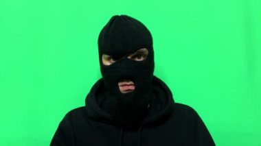 Kızgın genç adam bir hırsız oldu ve ilk mağaza soygunu için malzemelerini ve giysilerini yeşil bir arka planda hazırladı.