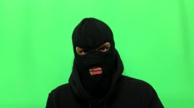 Kızgın genç adam bir hırsız oldu ve ilk mağaza soygunu için malzemelerini ve giysilerini yeşil bir arka planda hazırladı.