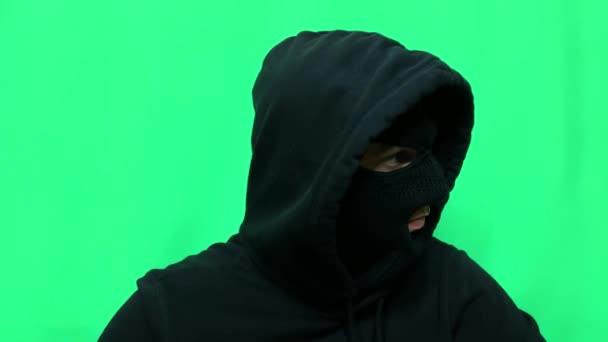 怒气冲冲的年轻人成了小偷 他把自己的装备和衣服都装扮成绿色背景 准备参加第一场商店劫案 — 图库视频影像