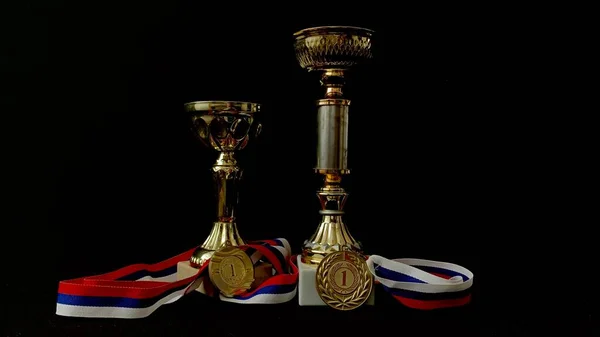 黒の背景に金 銅メダルとカップ 人々の前でのパフォーマンスと高レベルのスポーツの成果のための重要な賞の多数 — ストック写真