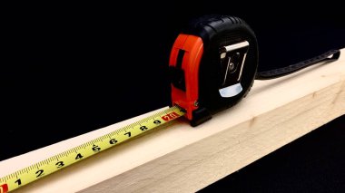 Meyve ağacından yapılmış ahşap bir çubuk, inşaat işi için el bandıyla ölçülür, tuvalin üzerindeki santimetre çubuğun uzunluğunu gösterir.