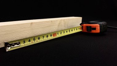 Meyve ağacından yapılmış ahşap bir çubuk, inşaat işi için el bandıyla ölçülür, tuvalin üzerindeki santimetre çubuğun uzunluğunu gösterir.