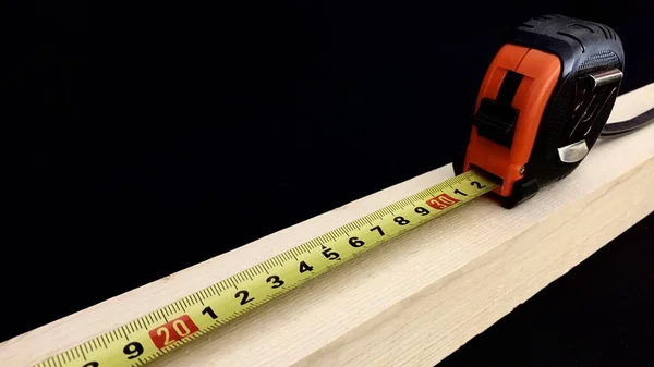 在建筑工程中 用手工胶带测量了一根由果树制成的木棍 帆布上的厘米显示了木棍的长度 — 图库照片