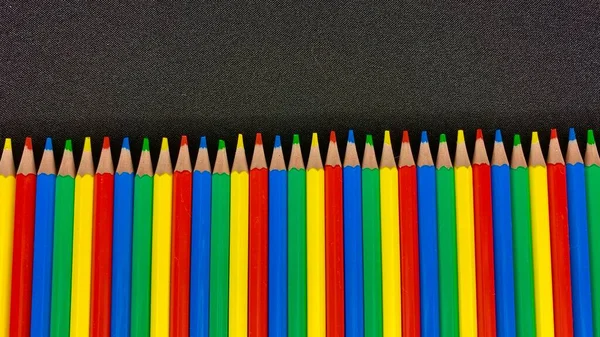 色彩艳丽的彩绘铅笔躺在一张黑色桌子上 — 图库照片