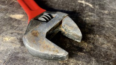 Atölye masasında kırmızı saplı eski ayarlanabilir bir anahtar var.