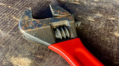 Atölye masasında kırmızı saplı eski ayarlanabilir bir anahtar var.