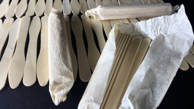 Farklı şekilli ahşap dondurma çubukları siyah bir masaya saçılmış.