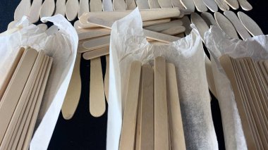 Farklı şekilli ahşap dondurma çubukları siyah bir masaya saçılmış.