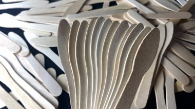 Farklı şekilli ahşap dondurma çubukları siyah bir masaya saçılmış.