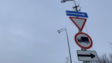 Kış mevsiminde kısıtlamalarla ilgili yol tabelaları bir direğe asılı.