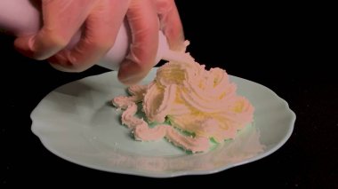 Vanilyalı krema ve beyaz bolonyadan çilek aromalı siyah bir masada duran bir tabağa sıkıştırılır, tatlı bir tatlı servis etmek için kirazlı