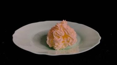 Vanilyalı krema ve beyaz bolonyadan çilek aromalı siyah bir masada duran bir tabağa sıkıştırılır, tatlı bir tatlı servis etmek için kirazlı