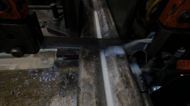 Atölyedeki usta metal için testereyle çalışıyor, makine bıçağı soğutmak için sabunlu su kullanarak çelik profili herhangi bir açıdan kesiyor.